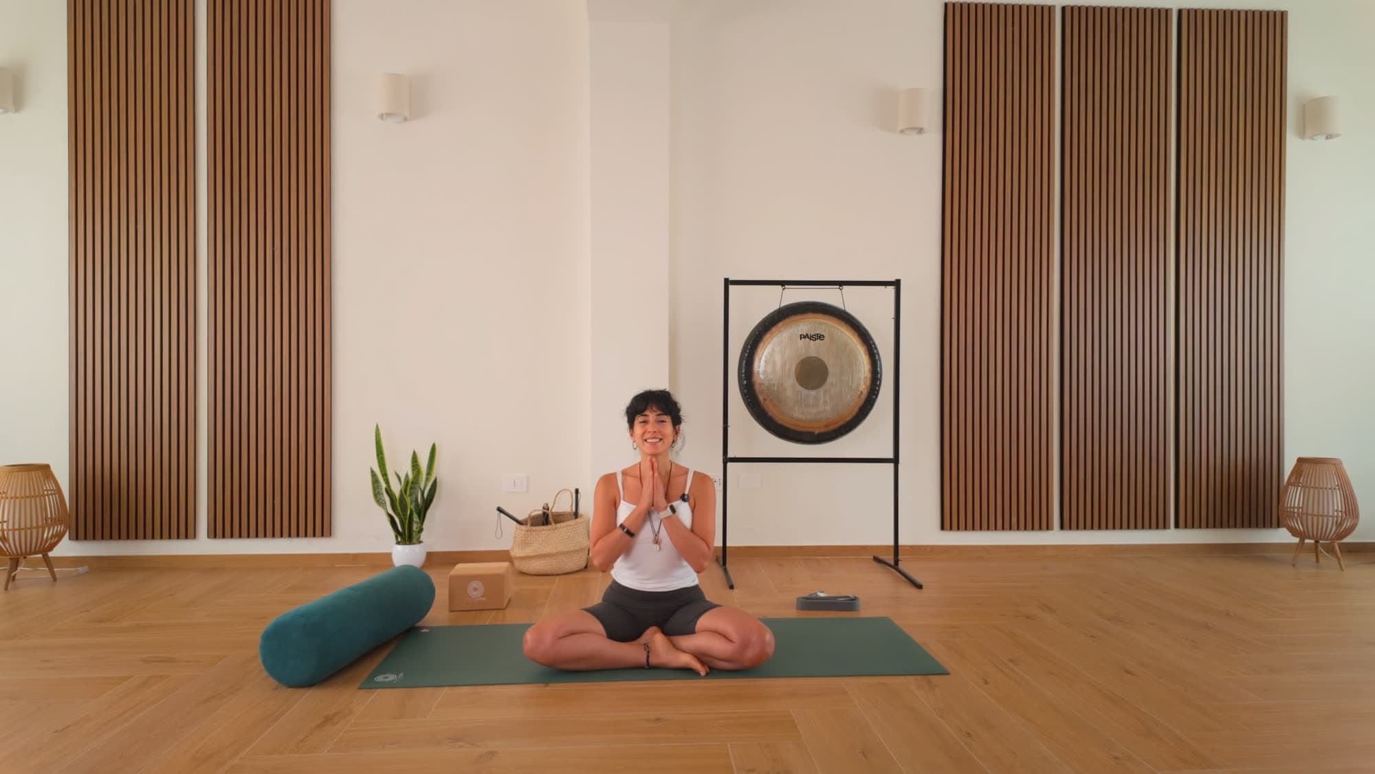 Martina Monterossi seduta sul tappetino nella sala di MaMo Yoga Studio, accanto al gong